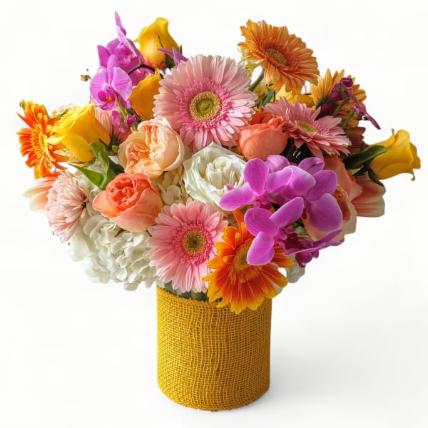 Bright mixed arrangement of pink gerberas, roses, orchids, and hydrangeas in a yellow textured vase