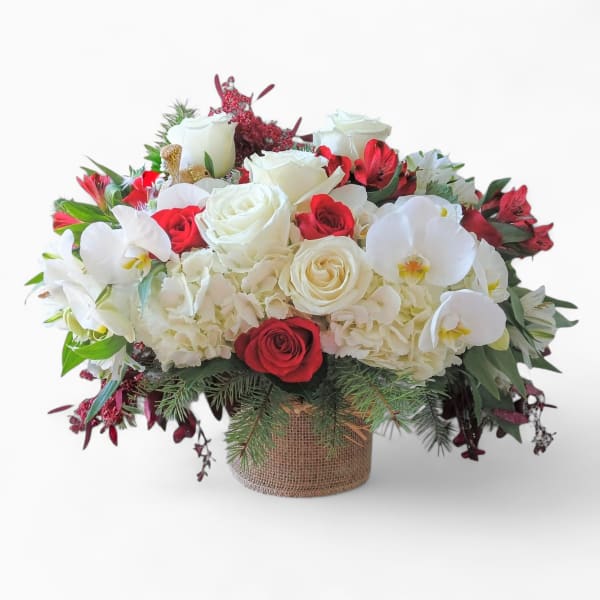 Low red and white arrangement with roses, orchids, and hydrangeas in a burlap-wrapped vase