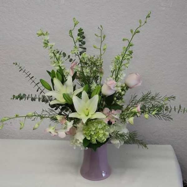 White lilies and pale pink flowers in a lavender vase