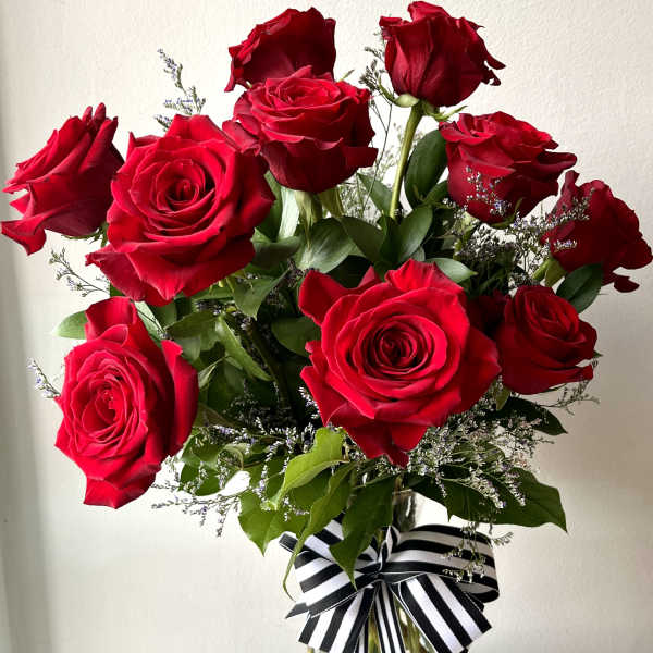 Bouquet of red roses in a clear glass vase with a striped ribbon