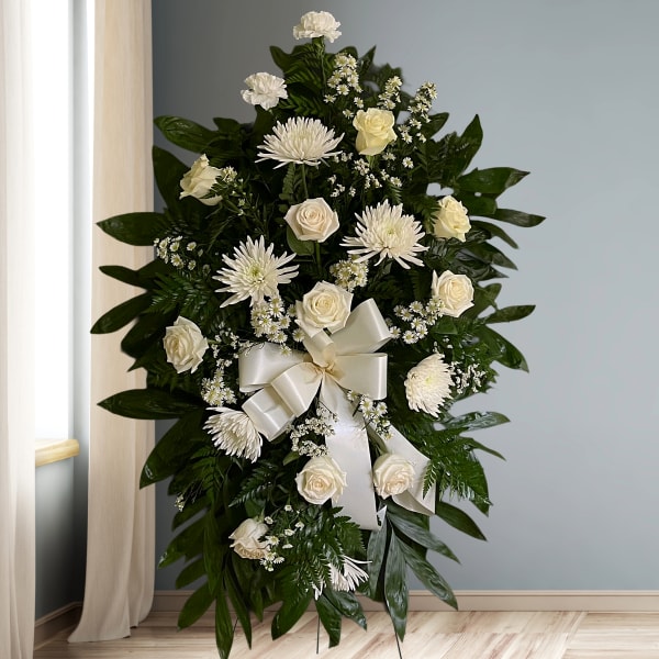 White floral standing spray with roses and chrysanthemums on dark greenery