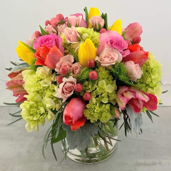 Colorful bouquet of roses and tulips in a clear glass vase