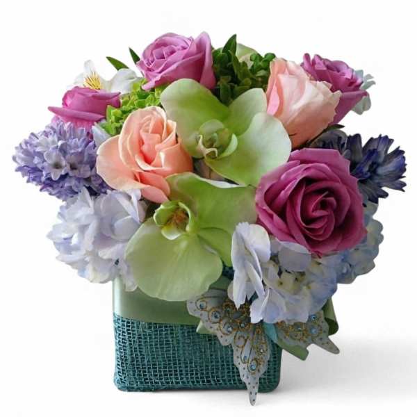 Colorful bouquet of roses, hydrangeas, and orchids in a square vase