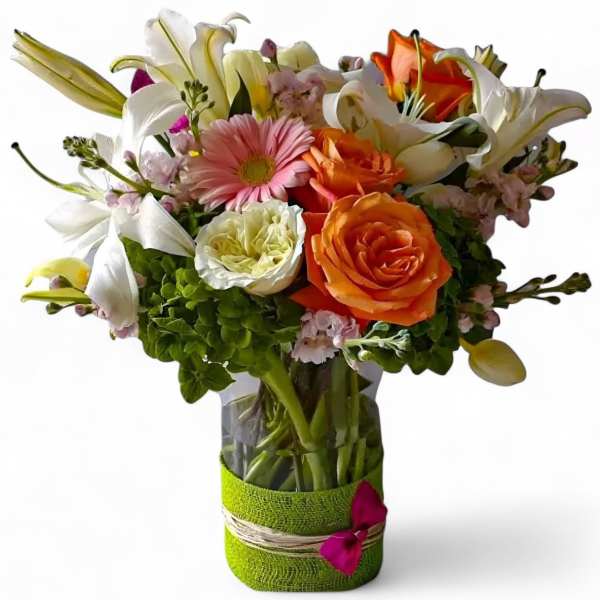 Mixed bouquet of lilies, roses, and gerbera daisies in a glass vase