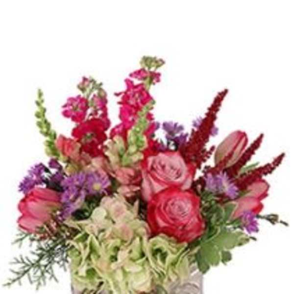 Mixed bouquet of pink, red, and purple flowers in a patterned vase