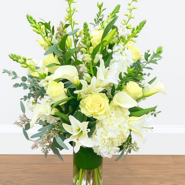 White and pale yellow floral arrangement in a glass vase