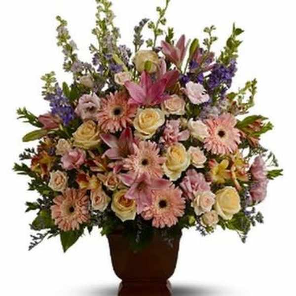 Mixed pink and cream flowers arranged in a brown urn vase