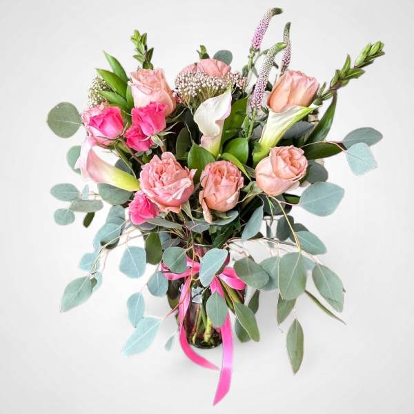 Pink and peach roses with white calla lilies in a glass vase