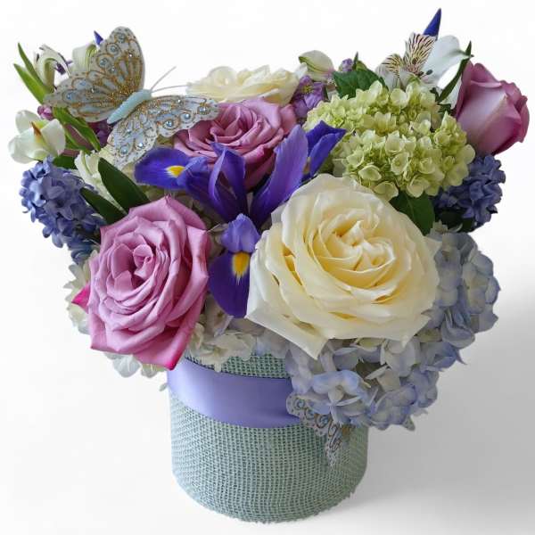 Bouquet of roses, hydrangeas, and irises in a wrapped box with a butterfly decoration
