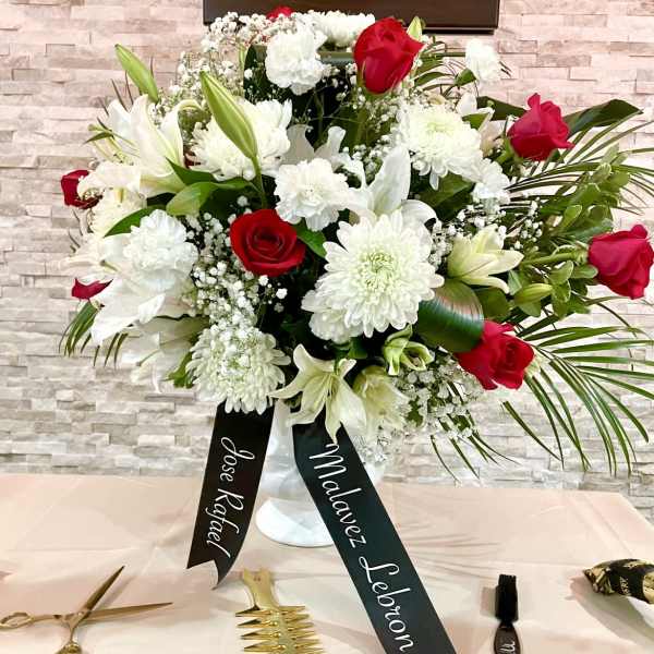 White and red floral arrangement in a vase with name ribbons