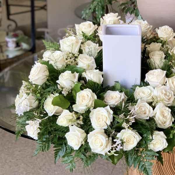 White rose wreath around a tall white vase centerpiece