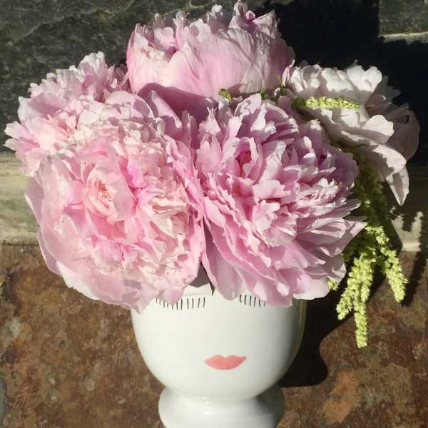 Pink peonies arranged in a white face-shaped vase