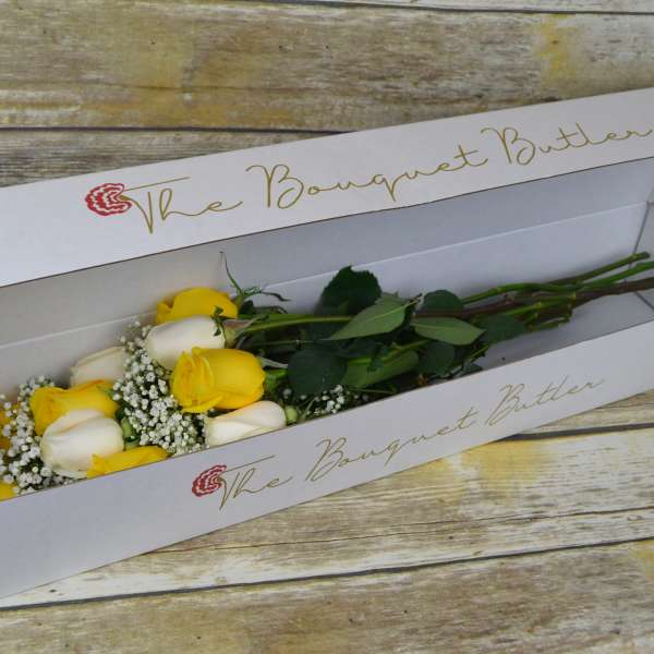 Yellow and white roses in a long white box