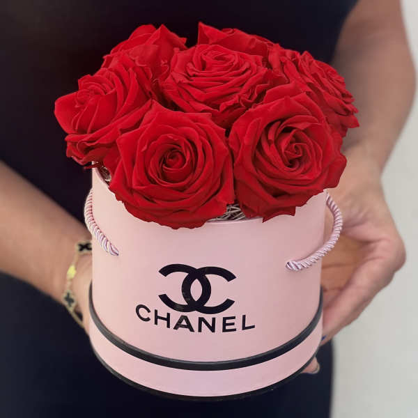 Red roses arranged in a pink round box with a Chanel logo