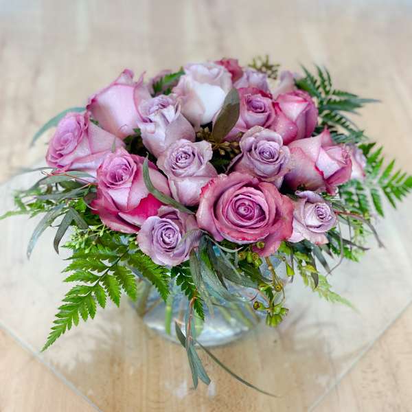 Pink and lavender roses arranged in a clear glass vase