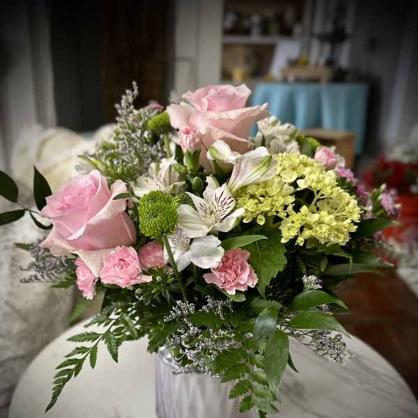 Pink roses and mixed flowers arranged in a clear glass vase