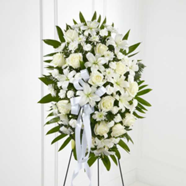 White floral standing spray with ribbon on an easel