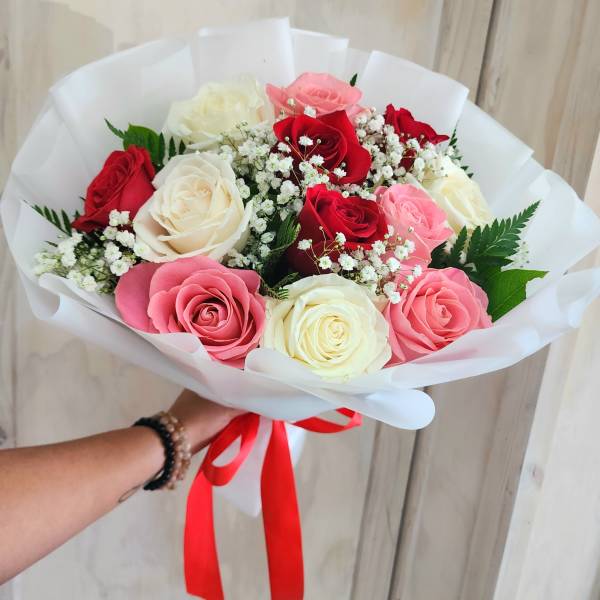 Handheld bouquet of red, pink, and white roses with baby's breath