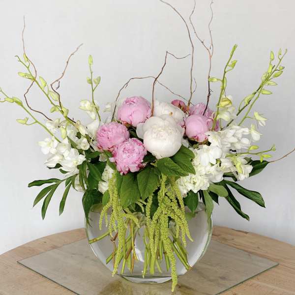 Pink and white peonies in a clear glass bowl vase