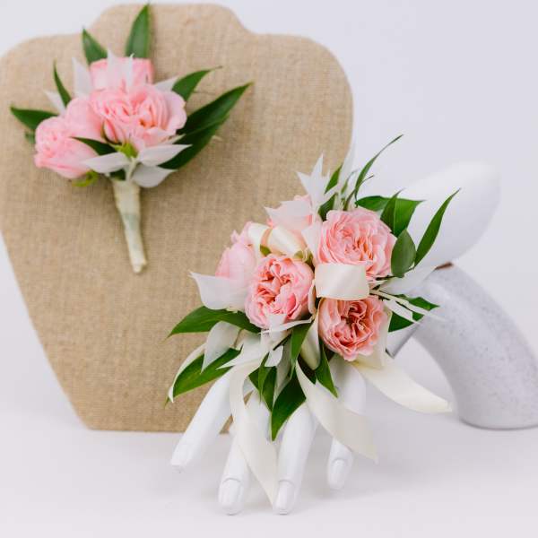 Pink rose boutonnieres with white ribbon on display stands