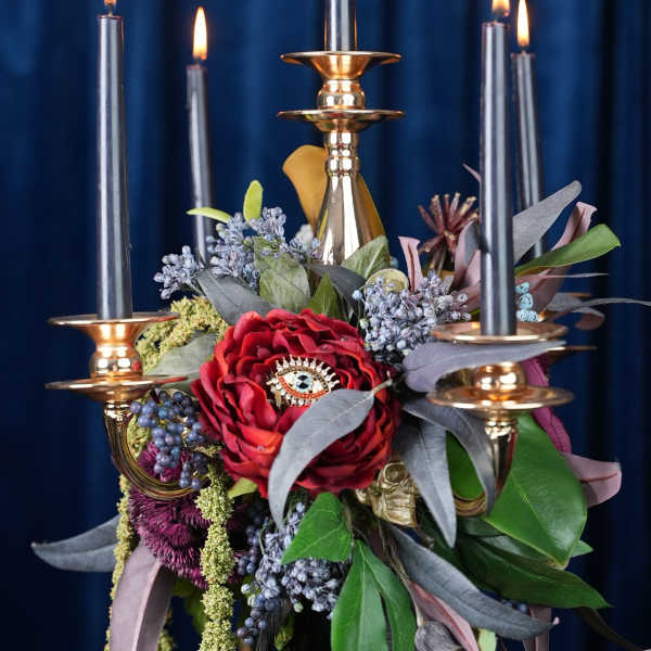 Red floral centerpiece with lit black candles in gold holders