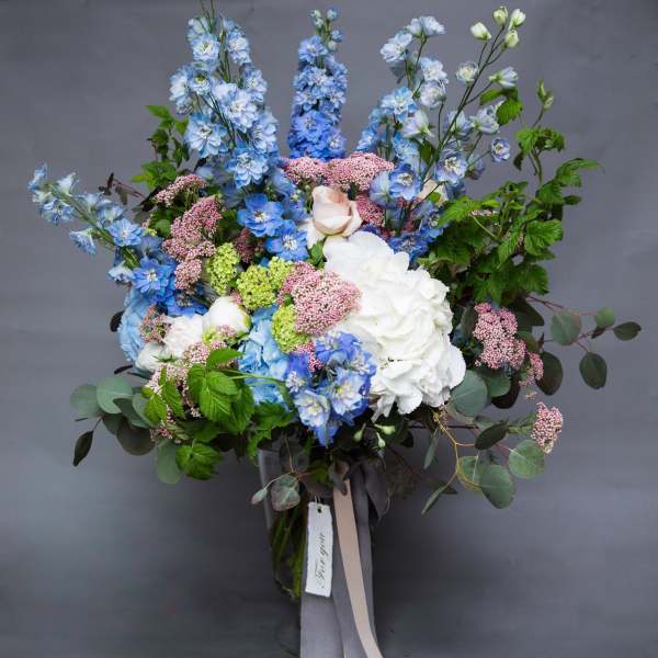 Large bouquet of blue and white flowers in a glass vase