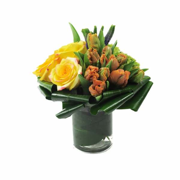 Yellow roses and orange tulips in a glass vase