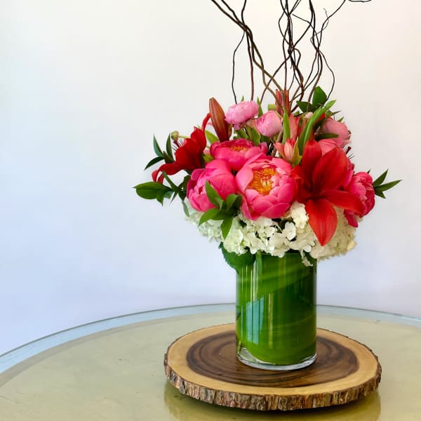 Pink and red flowers arranged in a green glass vase