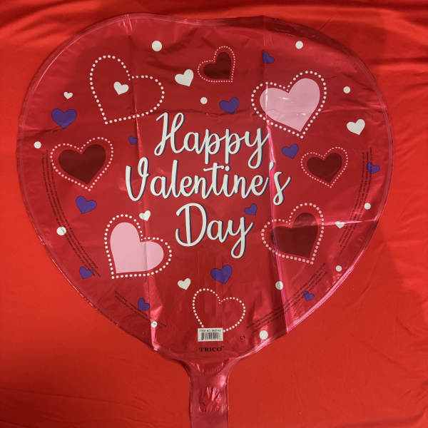 Heart-shaped Valentine’s Day foil balloon on a red background