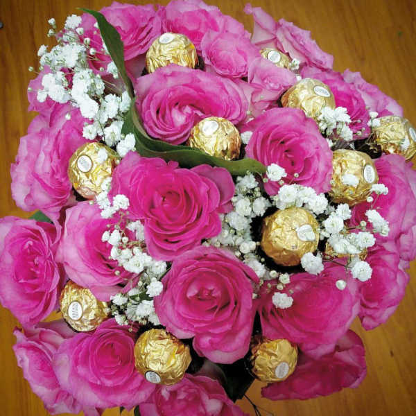 Bouquet of pink roses with white baby's breath and gold-wrapped chocolates