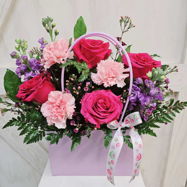 Pink roses and carnations in a lavender gift box with a ribbon handle