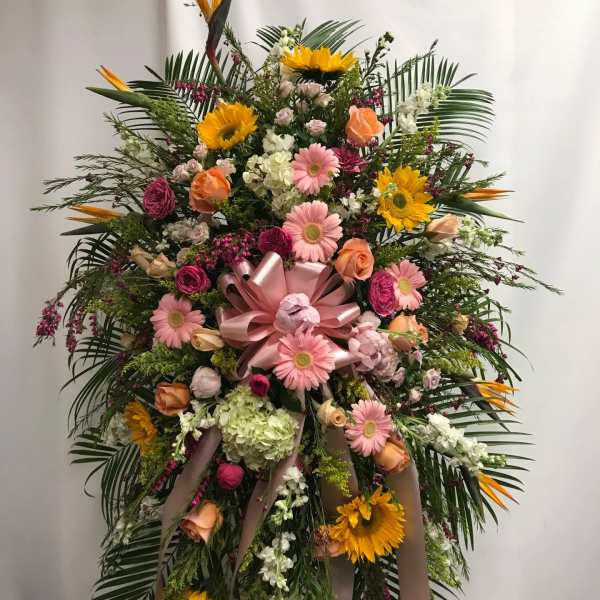Large standing floral spray with pink and yellow flowers and ribbon