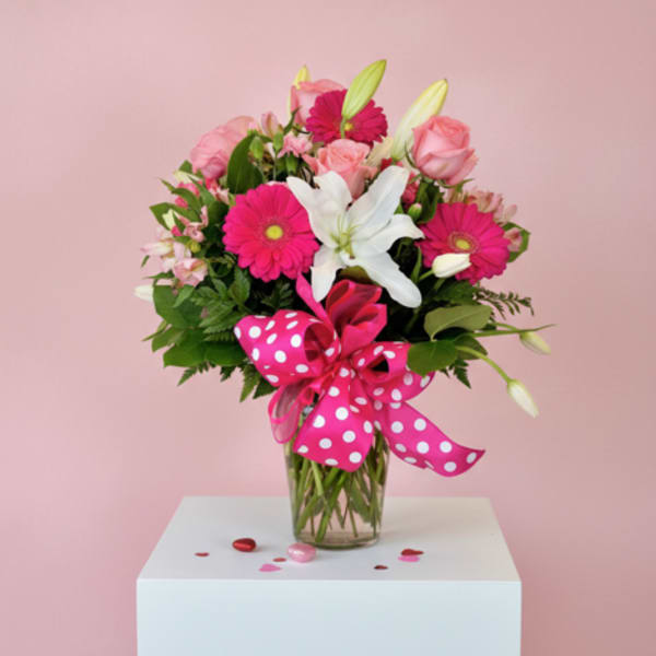 Pink and white bouquet in a glass vase with a polka-dot ribbon