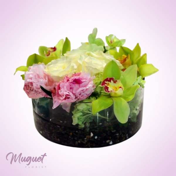 Pink and white flowers arranged in a black glass bowl