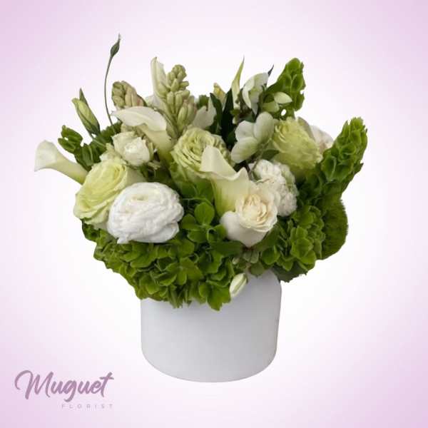 White and green floral arrangement in a white cylindrical vase