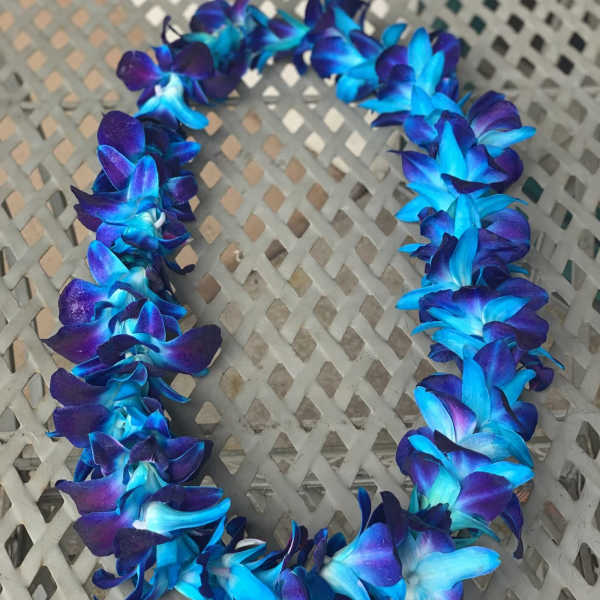 Blue and purple orchid lei on a woven chair