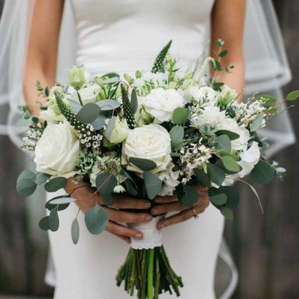 Bride holding a white bouquet with green foliage