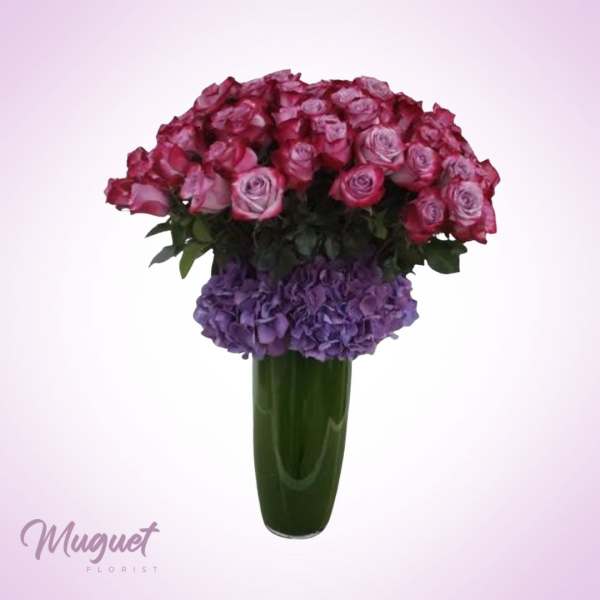 Pink roses and purple hydrangeas arranged in a tall green vase