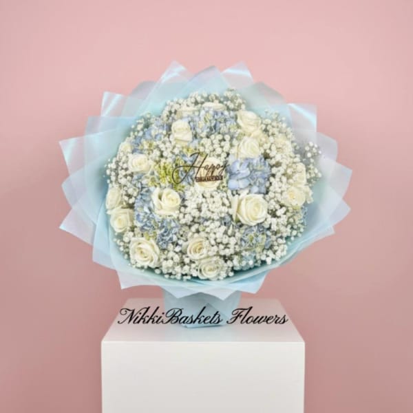 Round bouquet of white roses and baby’s breath wrapped in pale blue paper