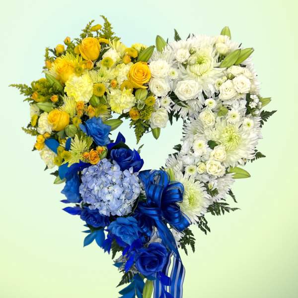 Heart-shaped bouquet of yellow, white, and blue flowers with a ribbon