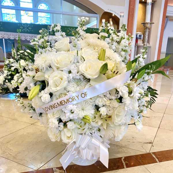 White funeral flower arrangement with a memorial ribbon