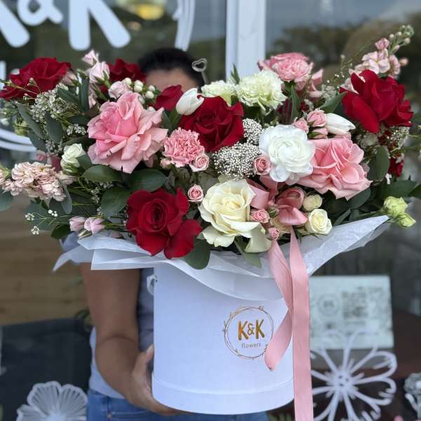 Large bouquet of red, pink, and white roses in a white hatbox with a pink ribbon.