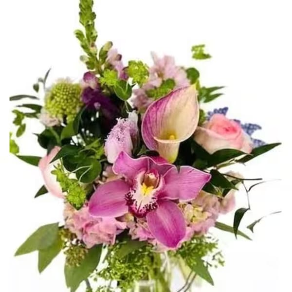 Mixed bouquet of pink orchids, calla lilies, roses, and hydrangea in a clear glass vase