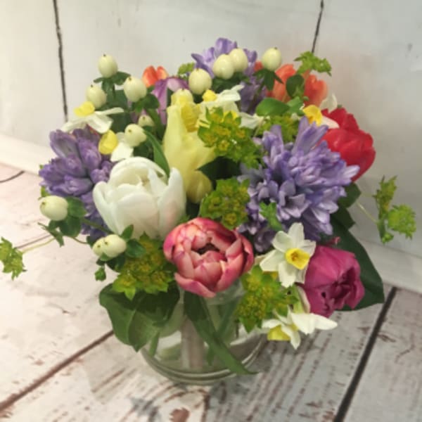Colorful mixed bouquet with tulips, hyacinths, and daffodils in a clear glass vase