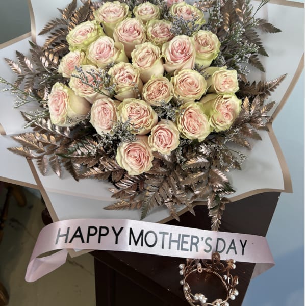 Bouquet of pale pink roses with metallic bronze foliage and a pink ribbon