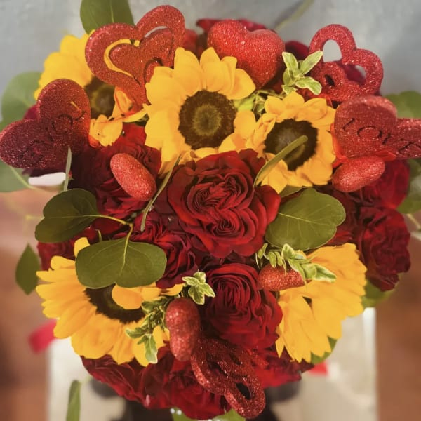Bouquet of red roses and yellow sunflowers with glittery heart picks