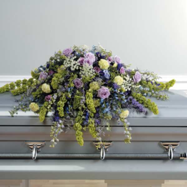 Pastel floral spray arranged on top of a gray casket