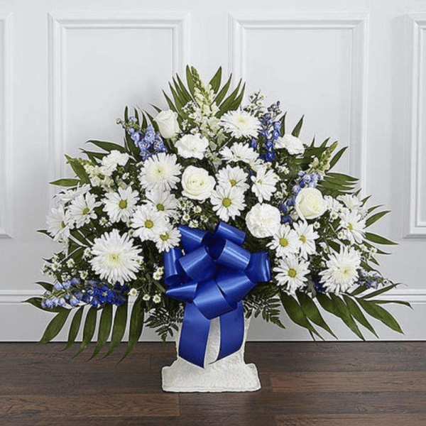 White floral standing spray with a blue ribbon on a pedestal base