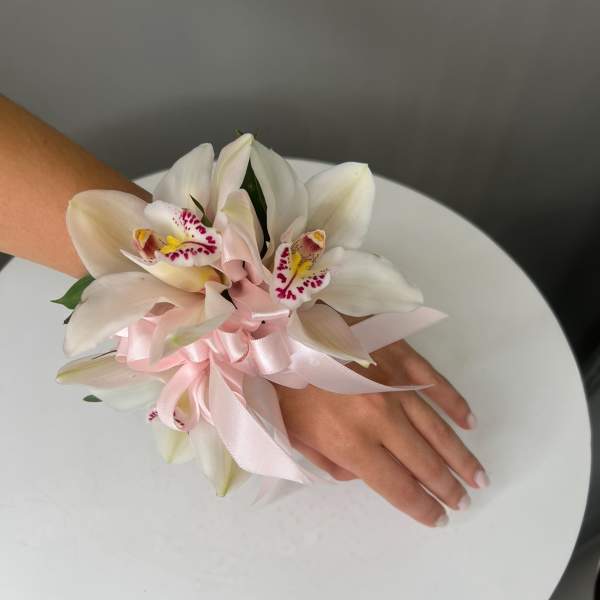 White orchid wrist corsage with a pink ribbon