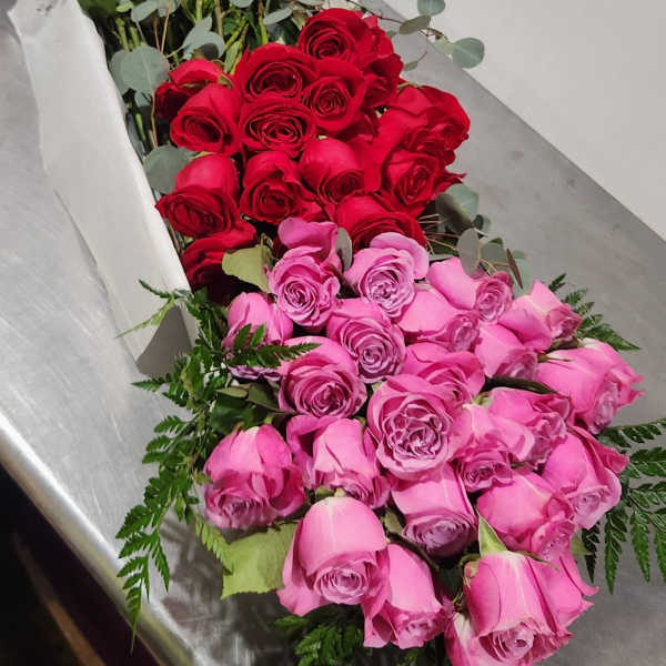 Three bunches of roses in pink, yellow, and red on a metal table